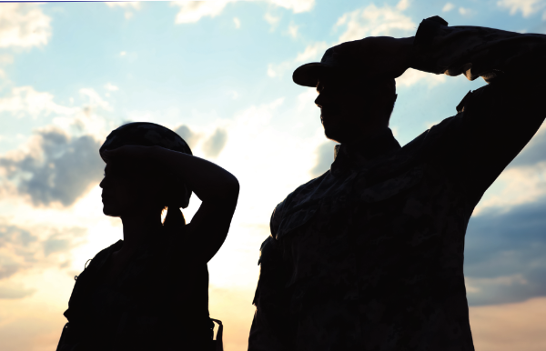 Two U.S. service members saluting at sunset